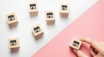 multipule blocks representing franchises with one being placed by hand in the best location.